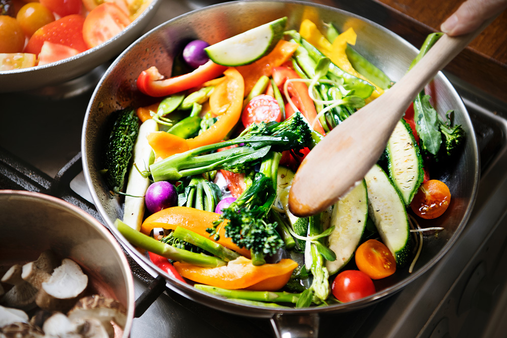 A colorful mix of vegetables sizzling in a pan on the stove, ready to be served.